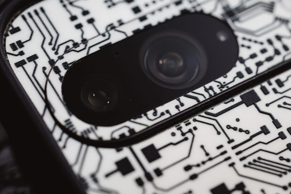 Macro shot of an electronic circuit design around a smartphone camera lens, showing intricate details.