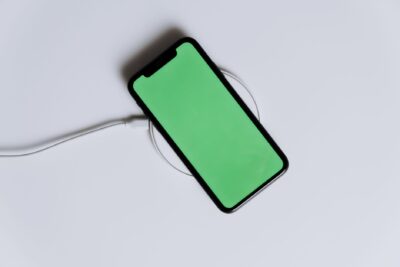 A minimalist smartphone with a green screen on a wireless charger, ideal for tech mockups.